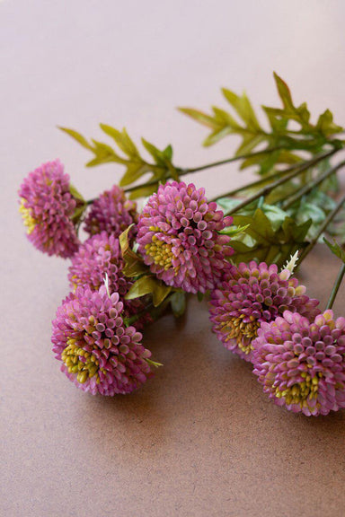 Bouquet of pink artificial flowers with green leaves on a beige background