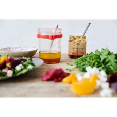 Salad ingredients and a jar of dressing on a wooden surface.