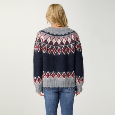 A woman viewed from behind wearing a fuzzy knit sweater with a Fair Isle pattern in navy blue, gray, and burgundy, paired with blue jeans against a plain light gray background.