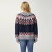 A woman viewed from behind wearing a fuzzy knit sweater with a Fair Isle pattern in navy blue, gray, and burgundy, paired with blue jeans against a plain light gray background.