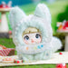 Toy figure of a character in a white hood with 'SHEEP' text, sitting on a grassy surface.