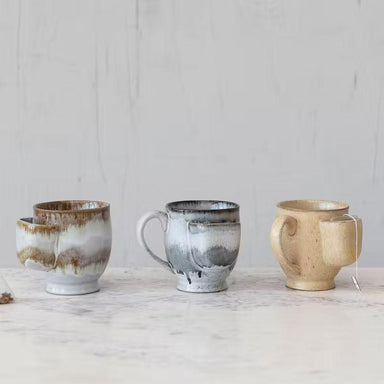 Four ceramic mugs with unique designs on a light wooden surface.