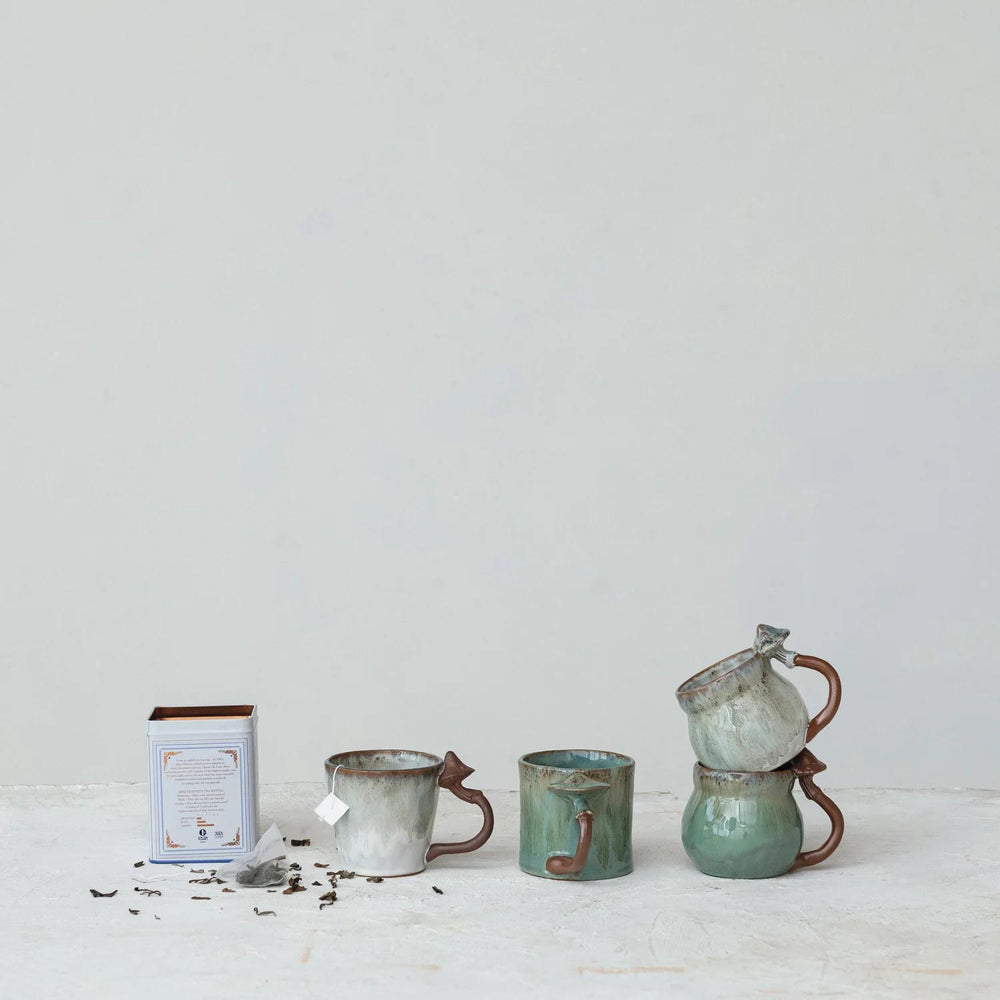 Set of ceramic mugs and a teapot on a light surface with a white background