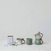 Set of ceramic mugs and a teapot on a light surface with a white background