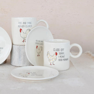 Set of mugs and plates with chicken illustrations and humorous text on a light background