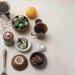 Collection of ceramic containers with various items on a light surface