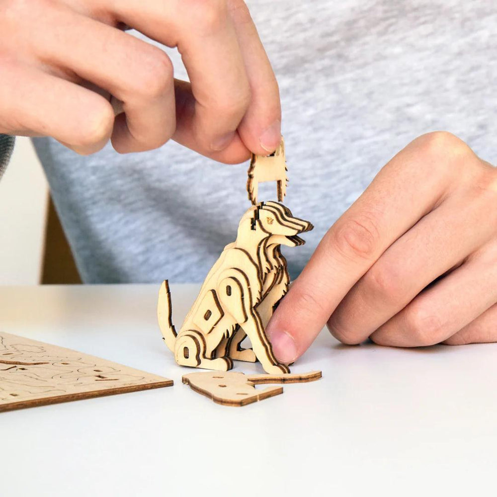 Person assembling a wooden dog puzzle on a white surface