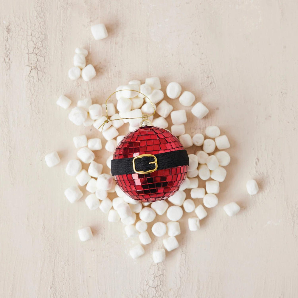 Red disco ball ornament with a black belt surrounded by white marshmallows on a beige background