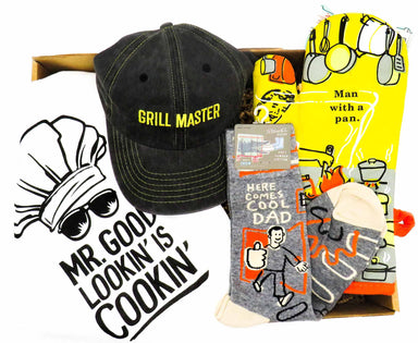 A delightful box filled with, the "Man With a Pan" oven mitt, a playful "Cool Dad" pair of socks, the "Grill Master" cap, and the "Mr. Good Looking is Cookin'" kitchen towel.