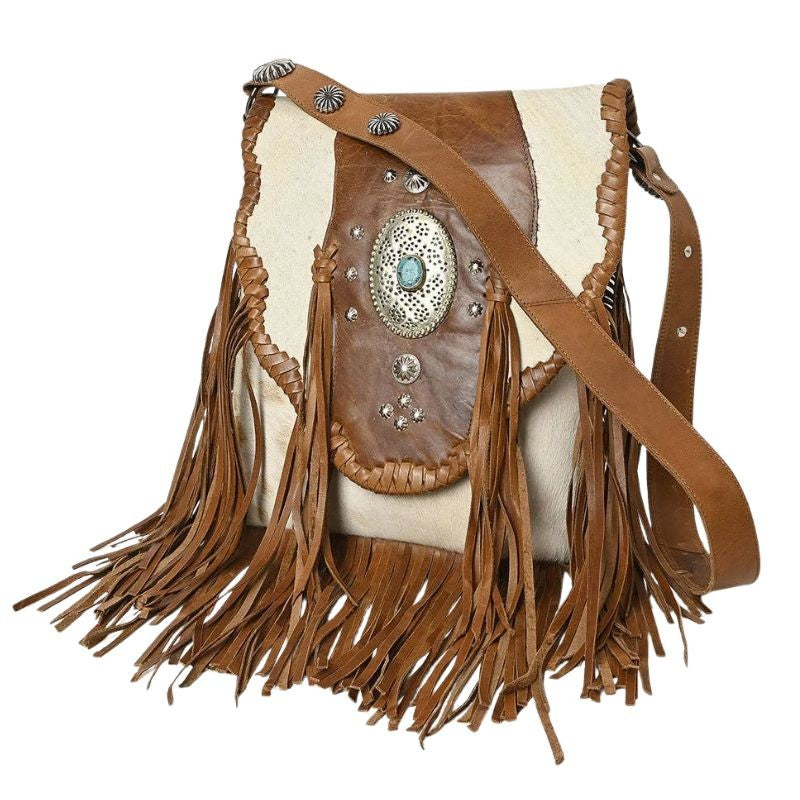 A western-style fringe shoulder bag made of brown leather and cream cowhide, decorated with silver conchos and a turquoise stone, shown on a white background.