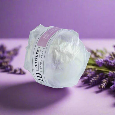 Bath bomb wrapped in plastic with 'mixture' branding on a purple background with lavender flowers.