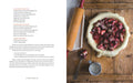 Pie with rhubarb filling on a wooden table with a rolling pin and measuring cup.