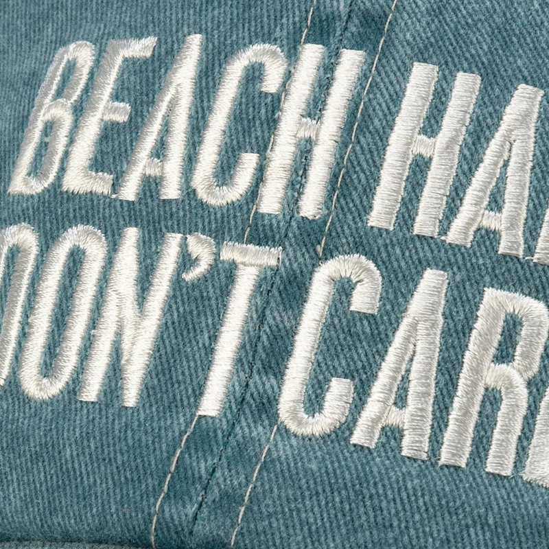Text 'BEACH HAIR DON'T CARE' embroidered on a denim fabric background