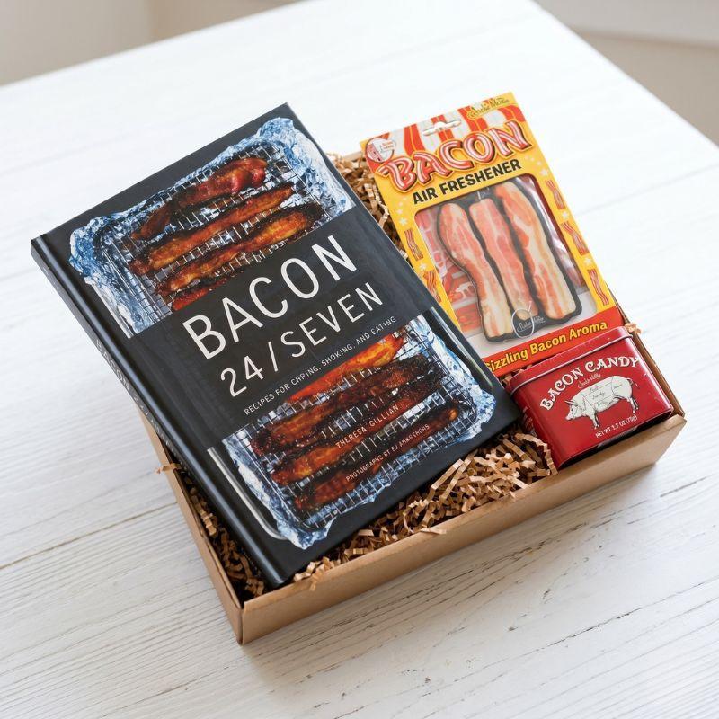 Gift set with 'Bacon 24/Seven' book and bacon-themed items on a white surface