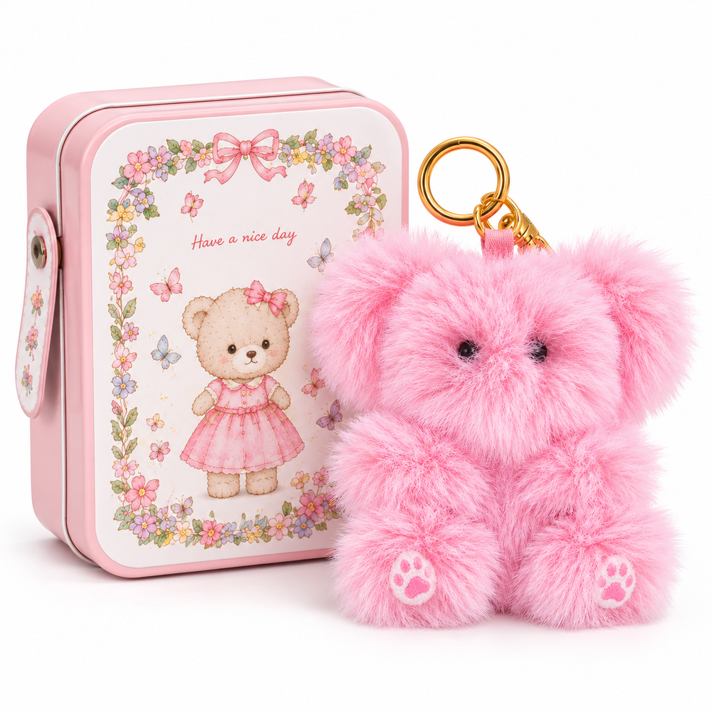 A pink teddy bear plush keychain with a gold key ring, shown next to a matching pink metal tin box featuring a teddy bear illustration and floral border.