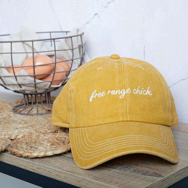 Yellow cap with 'free range chick' text on a wooden surface with eggs in the background