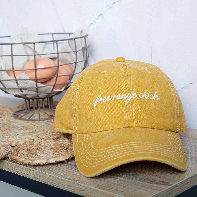 Yellow cap with 'free range chick' text on a wooden surface with eggs in the background