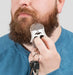 Person grooming a beard with a comb against a neutral background