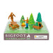 Toy set with Bigfoot and humans around a campsite, including a picnic table, campfire, and tent, on a white background.