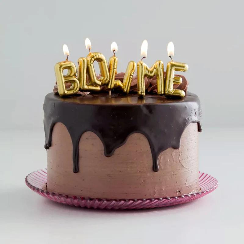 Chocolate cake with 'BLow Me' candles on a white background