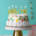 Birthday cake with 'BLow Me' balloons and colorful decorations on a turquoise background