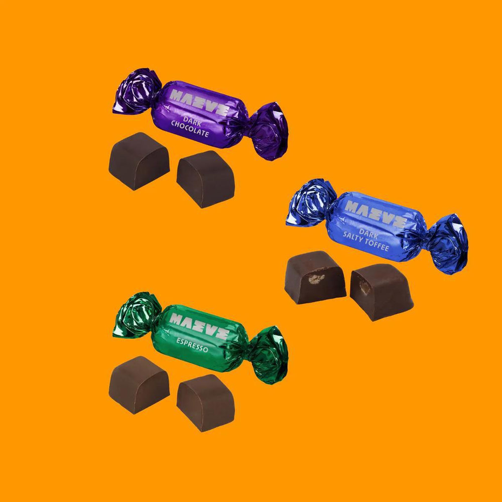 Assorted chocolate candies with colorful wrappings on an orange background