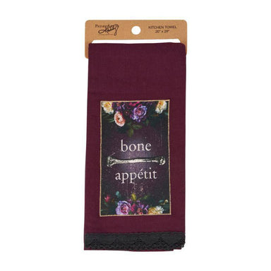 A maroon kitchen towel with a floral 'bone appetit' design, hanging from a kraft paper header card. The towel features a dark central panel with a floral border and the words 'bone appetit' in white, finished with a black lace trim at the bottom.
