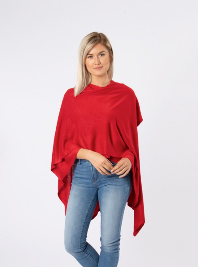 Woman wearing a red poncho and blue jeans on a white background