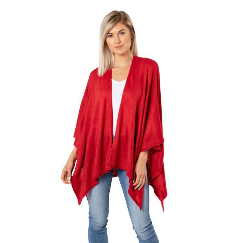 Woman wearing a red poncho over a white top and blue jeans on a white background