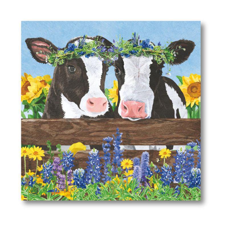 Two cows with flower crowns on a wooden fence with flowers and sunflowers in the background