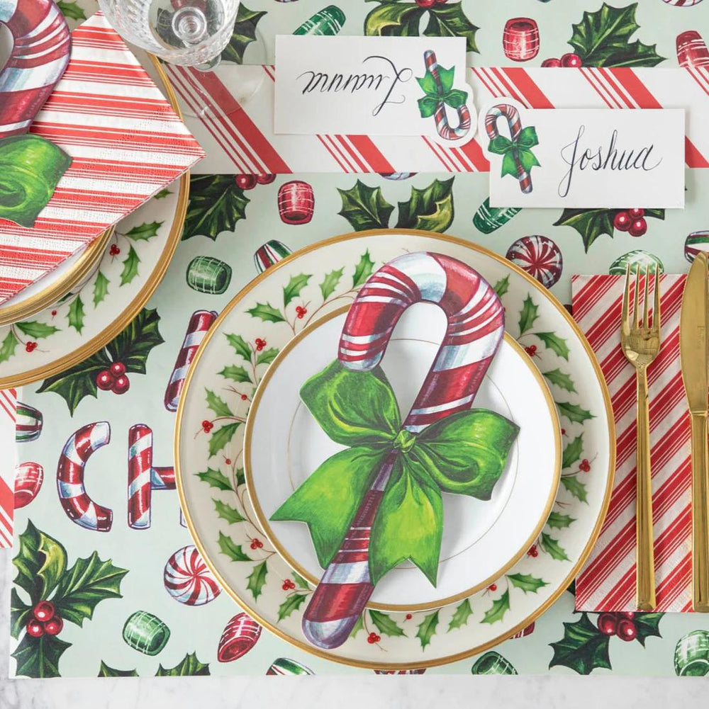 Christmas-themed table setting with candy cane design on plates and place cards.