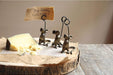 Decorative cheese stand with three small metal mice holding a sign over a block of cheese.