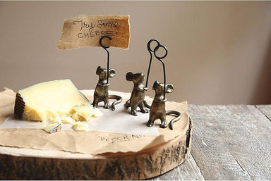 Decorative cheese stand with three small metal mice holding a sign over a block of cheese.