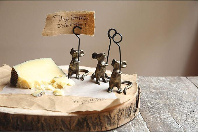Decorative cheese stand with three small metal mice holding a sign over a block of cheese.
