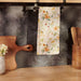 Floral towel hanging on a kitchen rack with wooden utensils and a cutting board.