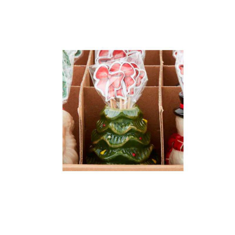 Decorative green Christmas tree-shaped candle with red berries in a cardboard box.