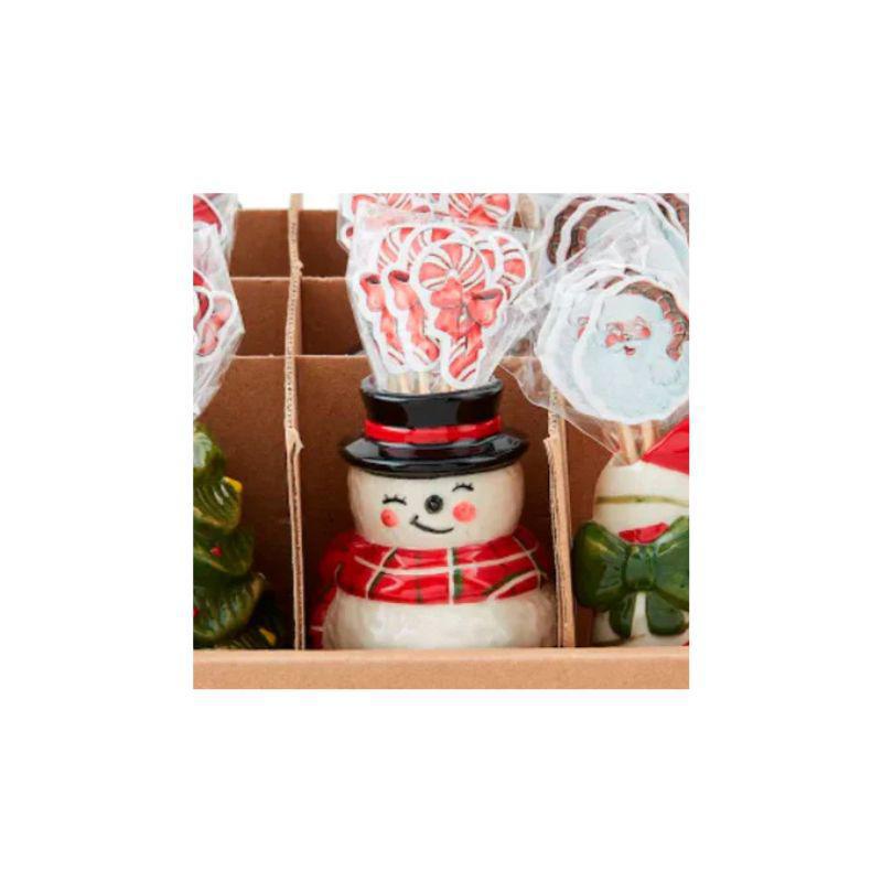 Snowman-shaped candy with a red scarf and black top hat in a box with other candies.