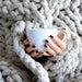 Taupe Chunky Knit Throw Blanket sourranding someone holding a cup