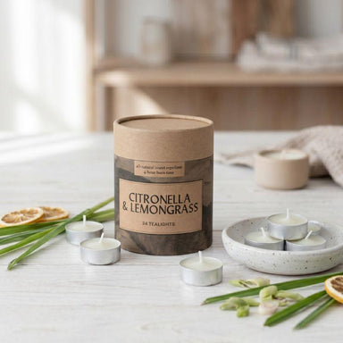 Candle packaging labeled 'Citronella & Lemongrass' with lit tealights on a wooden surface.