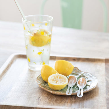 Glass of lemon water with lemons on a tray