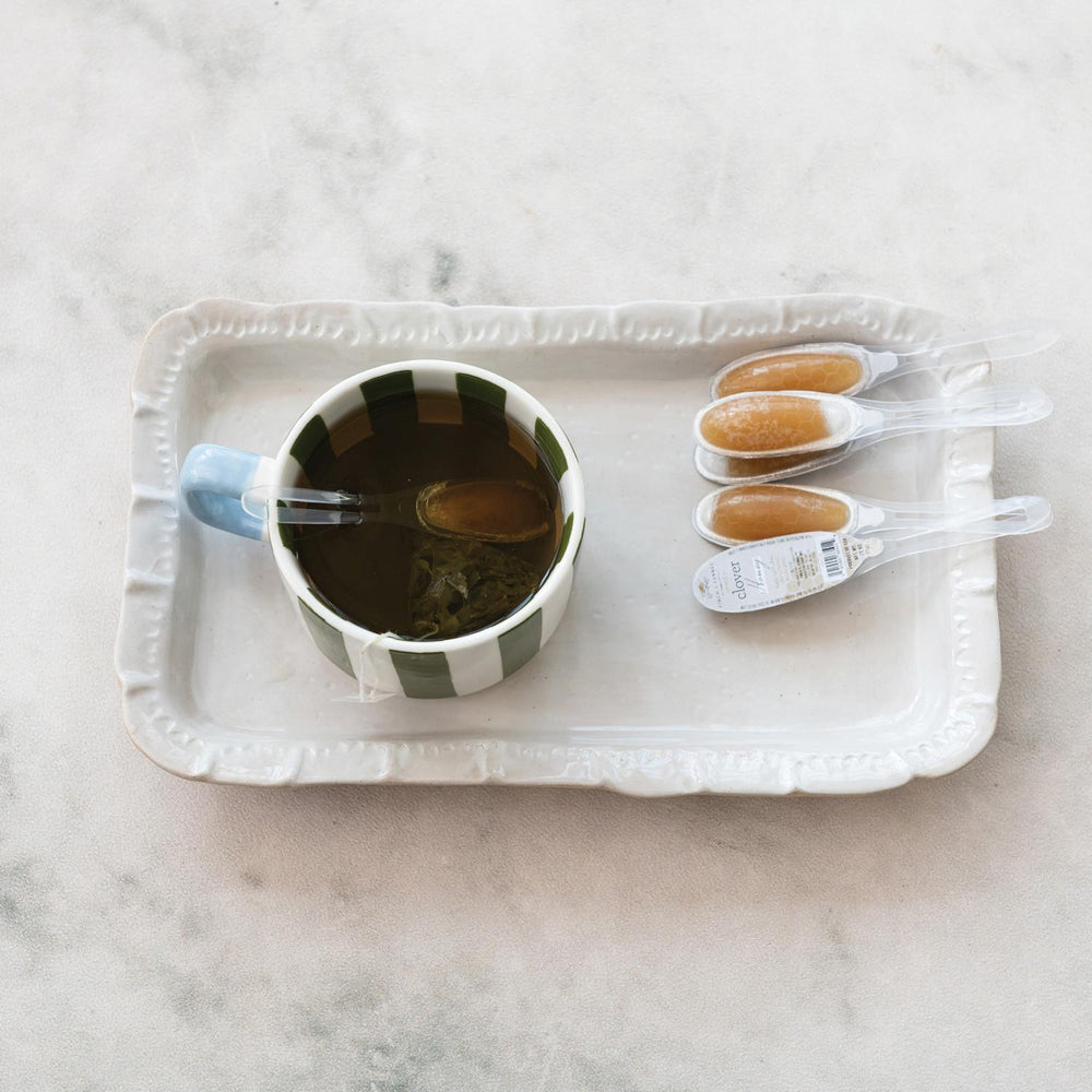 Cup of tea with honey on a white tray on a marble surface