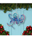 Decorative octopus ornament hanging on a Christmas tree with red ornaments and green branches.