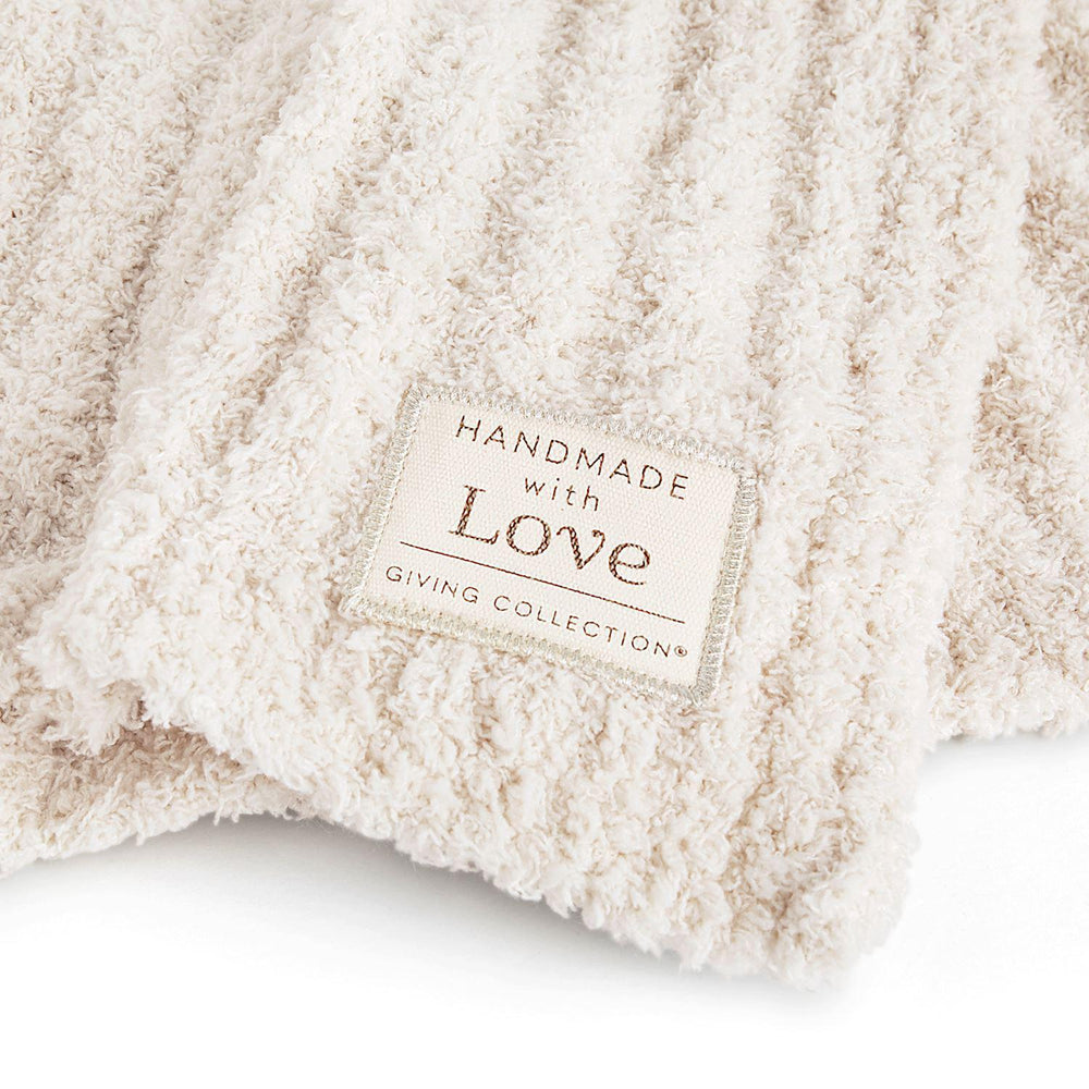 Close-up of a beige textured blanket with a 'Handmade with Love' label.