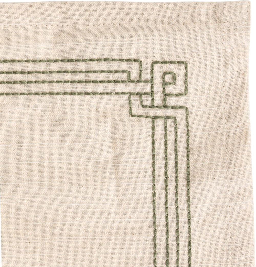 Close-up of a textured fabric with geometric embroidery on a beige background