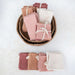 Folded fabric sheets in pink and beige colors arranged in a wicker basket on a white background.