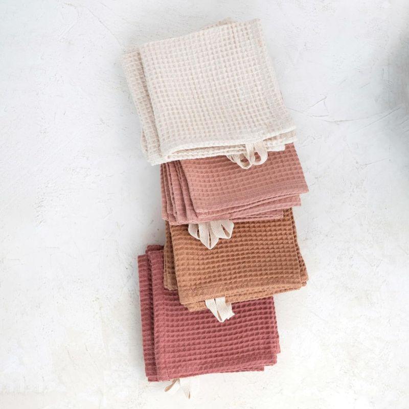 Stack of waffle-textured towels in various colors on a white background