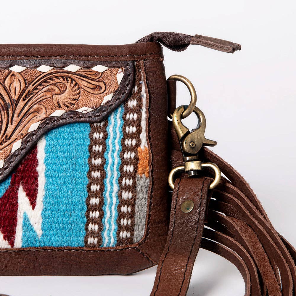 Close-up of a brown leather handbag with intricate patterns and a decorative strap.