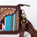 Close-up of a brown leather handbag with intricate patterns and a decorative strap.