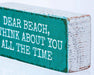 Wooden block with text 'Dear Beach, think about you all the time' on a snowy background