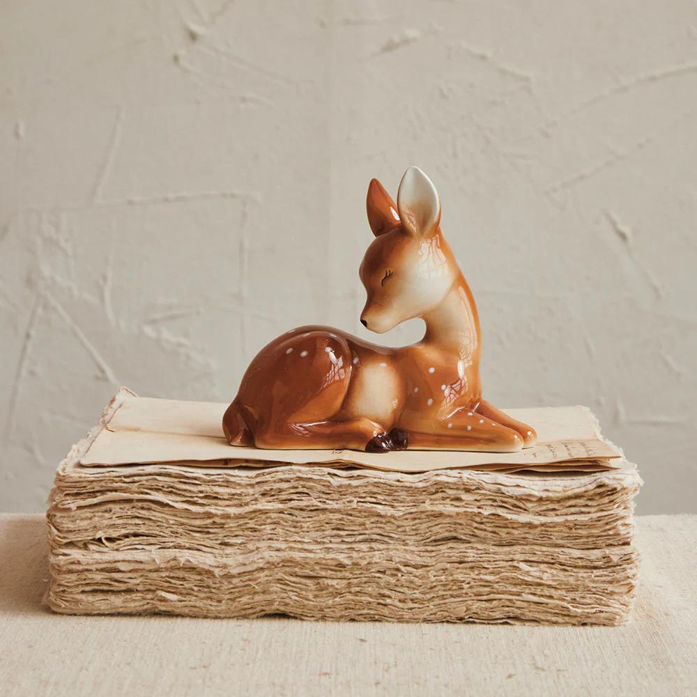 Deer figurine on a stack of books with a textured wall background